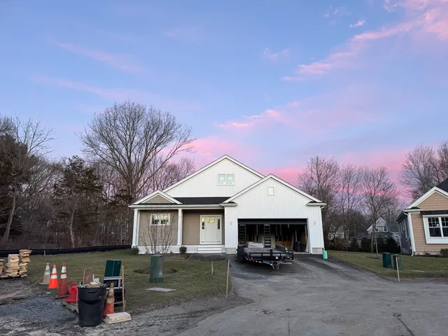a front view of a house with a yard and large tree