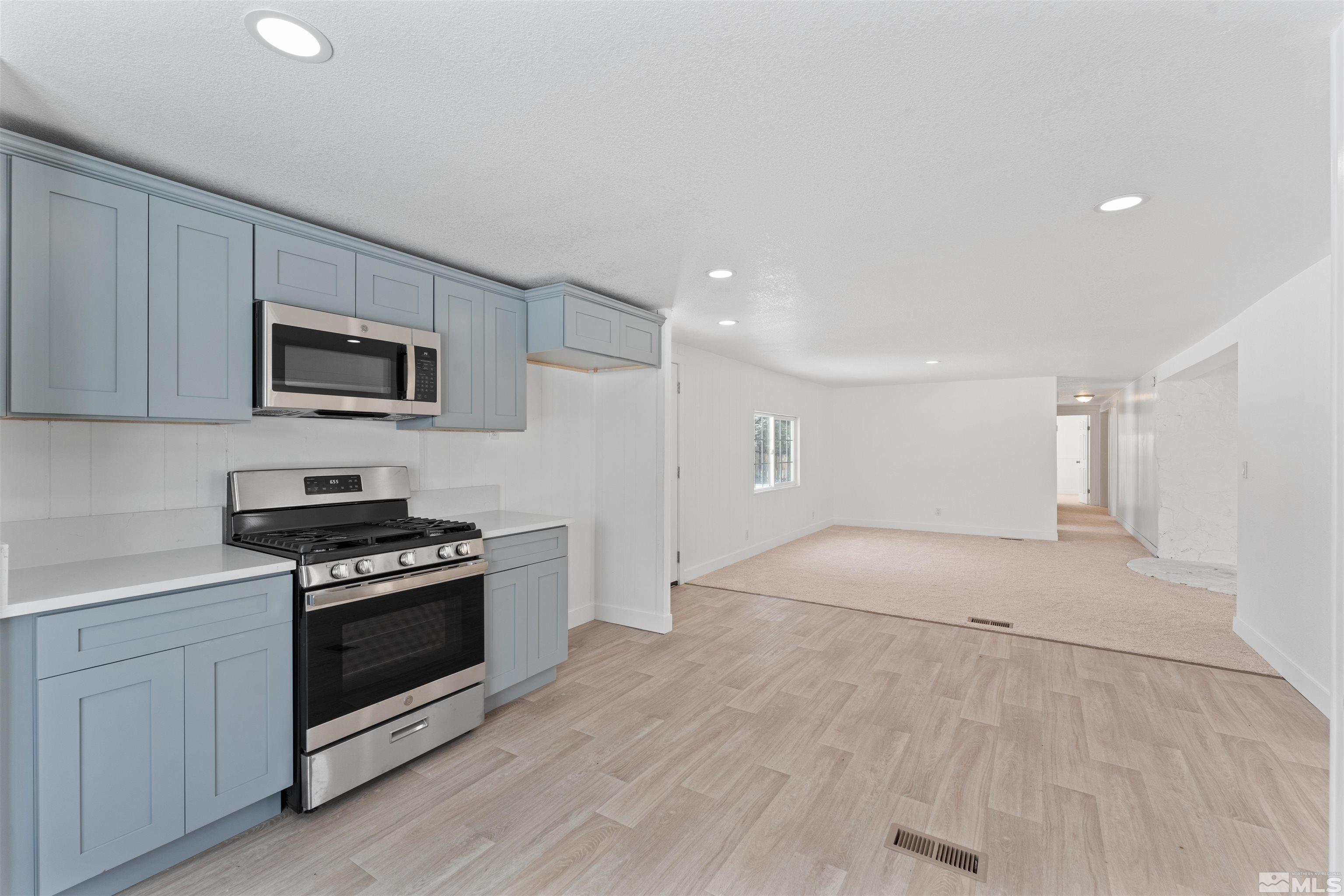 a kitchen with a stove a microwave and white cabinets