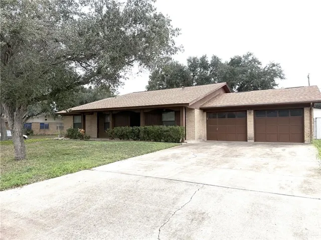 a front view of a house with a garden and trees