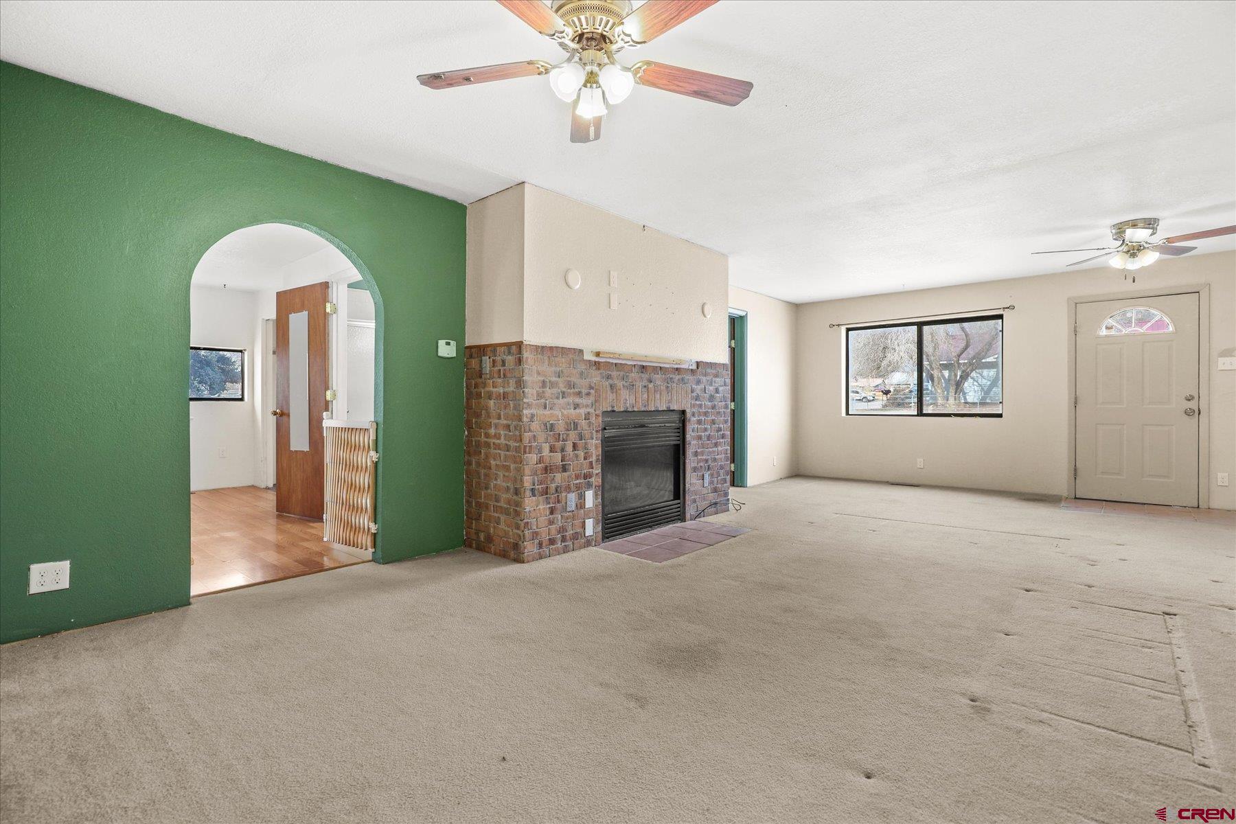 403 East 3rd Street Cortez, CO 81321 - Photo 6 of 31 a view of a livingroom with a fireplace a ceiling fan and windows