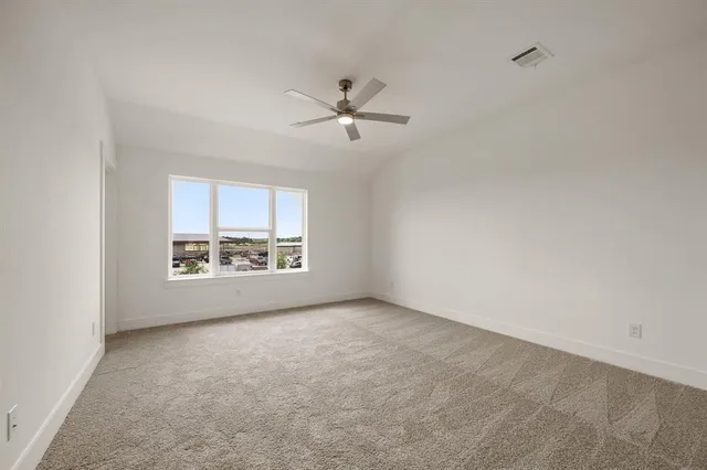 an empty room with a ceiling fan and window