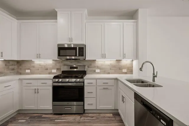 a kitchen with stainless steel appliances granite countertop a stove a sink and a microwave