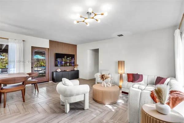 a living room with furniture kitchen view and a large window