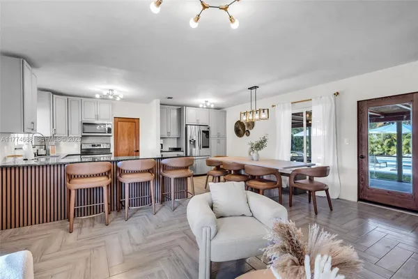 a view of a dining room and livingroom with furniture wooden floor a chandelier