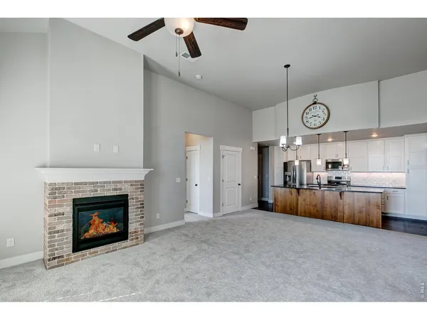 a view of a livingroom with a fireplace a ceiling fan and windows