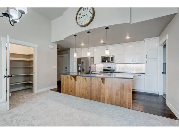 a kitchen with stainless steel appliances granite countertop a refrigerator a sink dishwasher a stove and white countertops with wooden floor