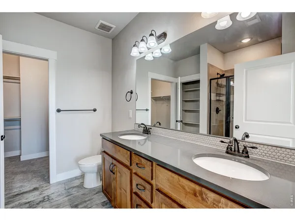 a bathroom with a granite countertop double vanity and a mirror