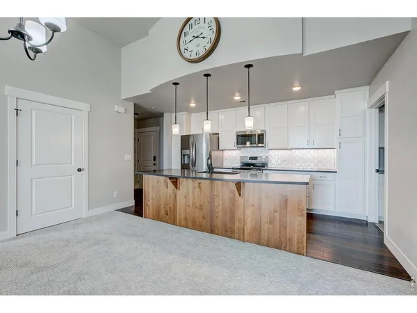 a kitchen with stainless steel appliances granite countertop a stove a sink and a refrigerator with wooden floor
