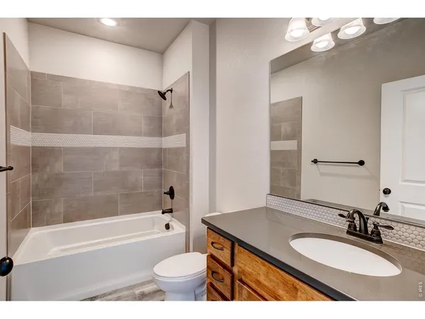 a bathroom with a granite countertop sink toilet mirror and bathtub