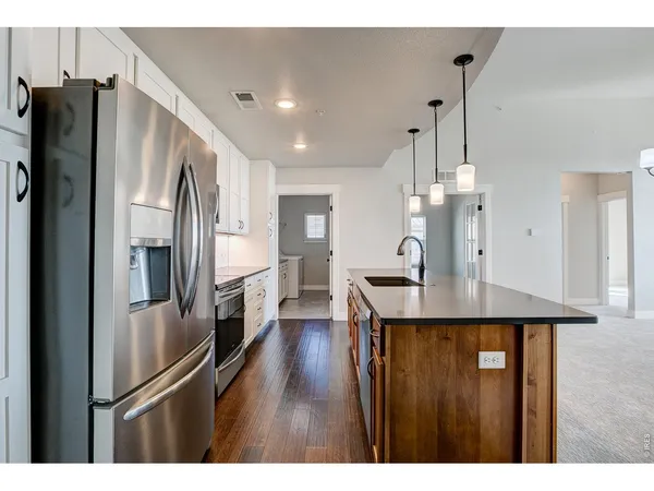 a kitchen with stainless steel appliances kitchen island a refrigerator and a wooden cabinets