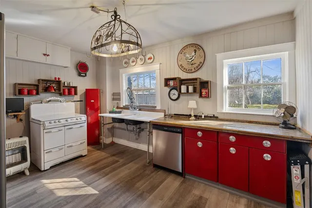 a very nice looking kitchen with granite countertop a stove a sink dishwasher and wooden floors