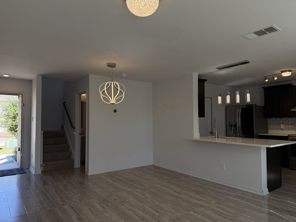 709 Yearwood Lane, Unit 48E Jarrell, TX 76537 - Photo 14 of 39 an entryway with wooden floor and a kitchen