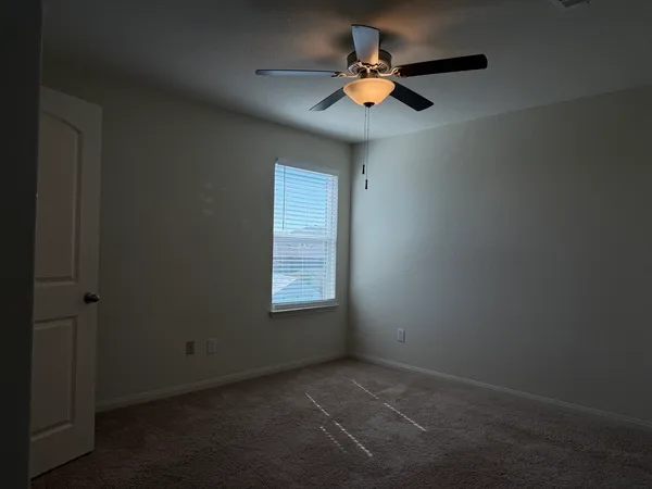 an empty room with a window and a fan