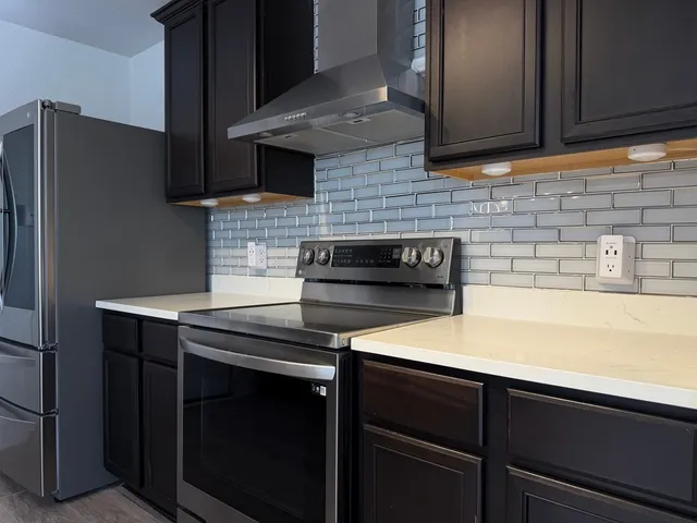 a kitchen with stainless steel appliances a stove and a refrigerator with wooden cabinets