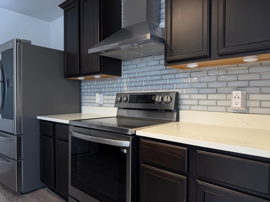 709 Yearwood Lane, Unit 48E Jarrell, TX 76537 - Photo 8 of 39 a kitchen with stainless steel appliances a stove and a refrigerator with wooden cabinets