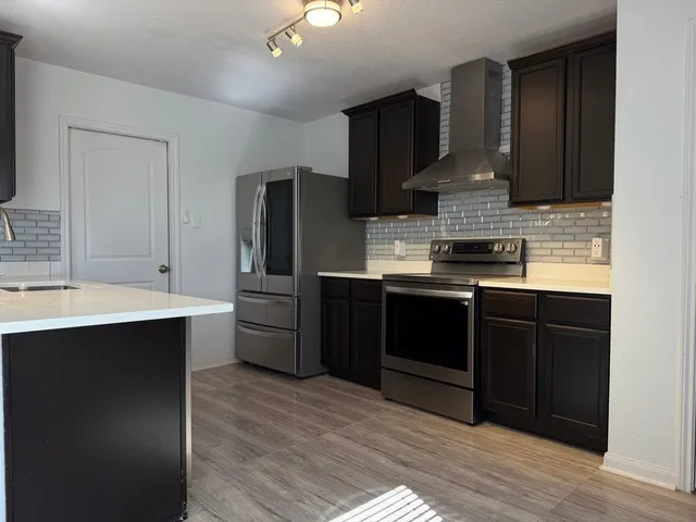 a kitchen with stainless steel appliances kitchen island granite countertop a sink stove and refrigerator