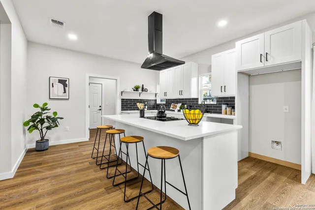 a kitchen with stainless steel appliances granite countertop a refrigerator a stove a microwave oven a dining table and chairs with wooden floor