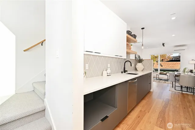 a large white kitchen with a sink and dishwasher a stove with wooden floor