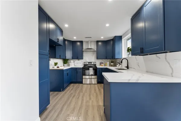 a large kitchen with stainless steel appliances granite countertop a stove refrigerator a oven and a sink with wooden floor