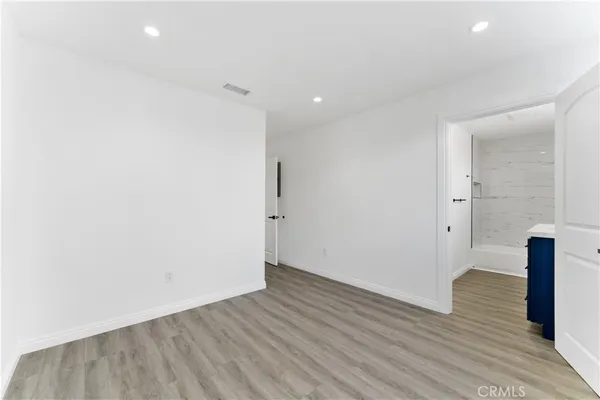a view of an empty room with wooden floor and a mirror