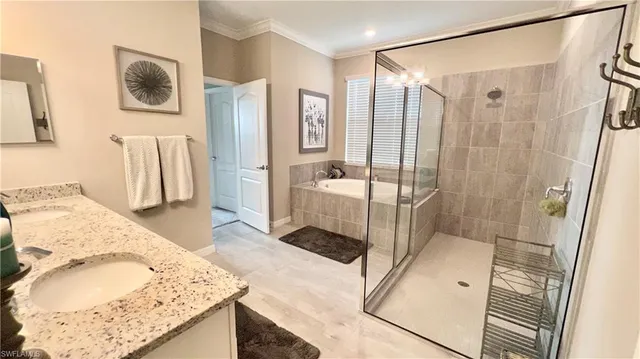 a en suite spacious bathroom with a granite countertop double vanity sink a mirror and a shower