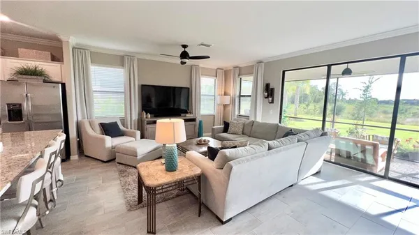 a living room with furniture floor to ceiling window hardwood floor and a flat screen tv