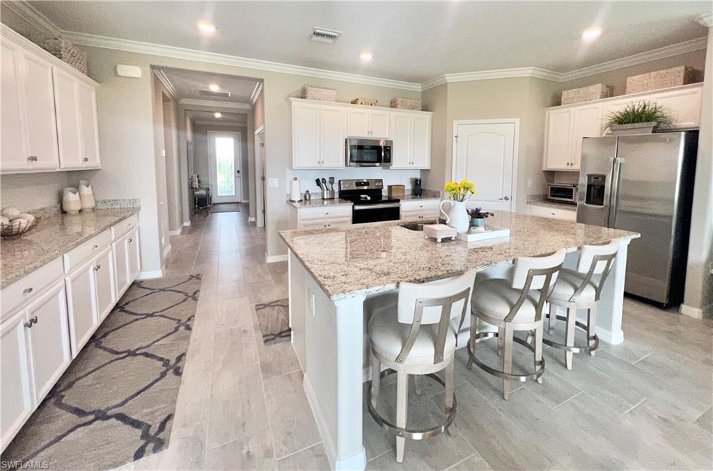 19824 Beechcrest Place Estero, FL 33928 - Photo 5 of 26 a kitchen with stainless steel appliances granite countertop a stove top oven a refrigerator a sink and white cabinets