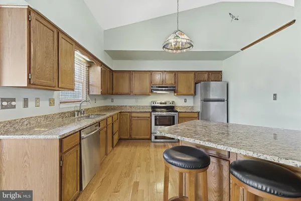 a kitchen with stainless steel appliances granite countertop a sink a stove and a refrigerator