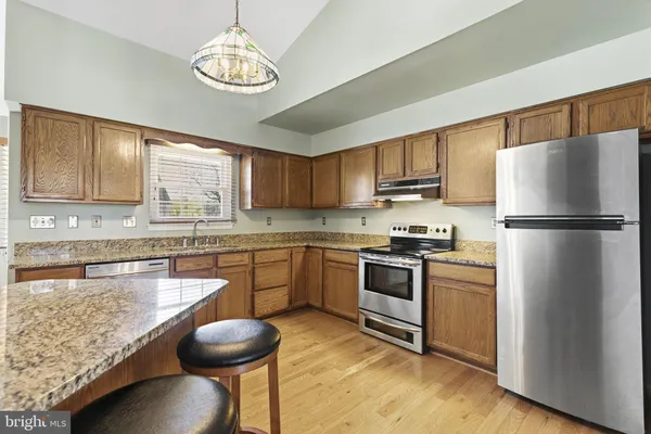 a kitchen with granite countertop a stove refrigerator and microwave