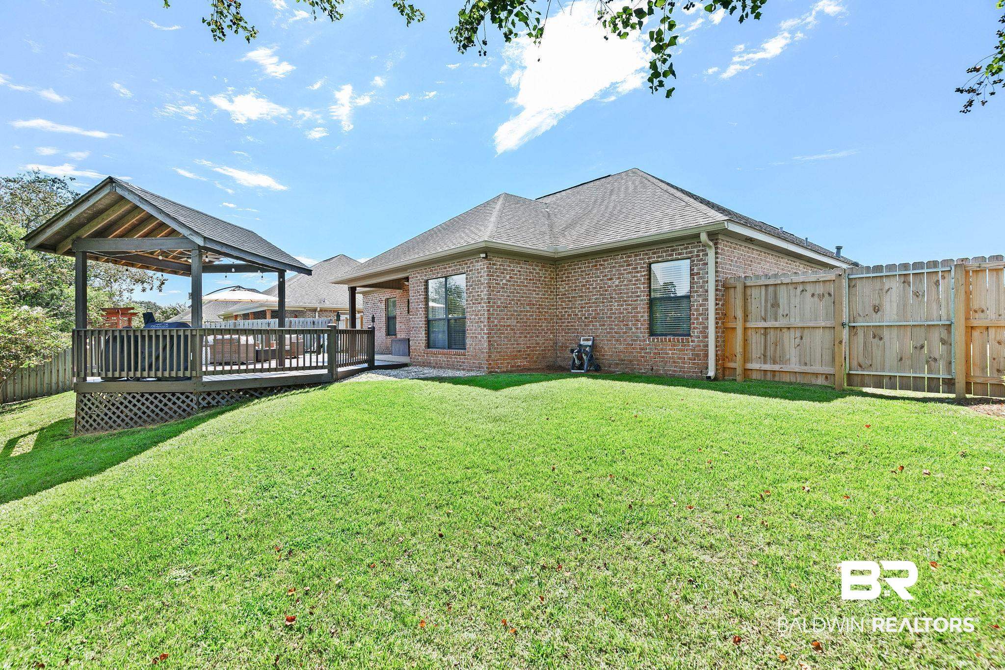 9522 Sanibel Loop Daphne, AL 36526 - Photo 37 of 43 Back of property featuring brick siding, a deck, a shingled roof, and a fenced backyard