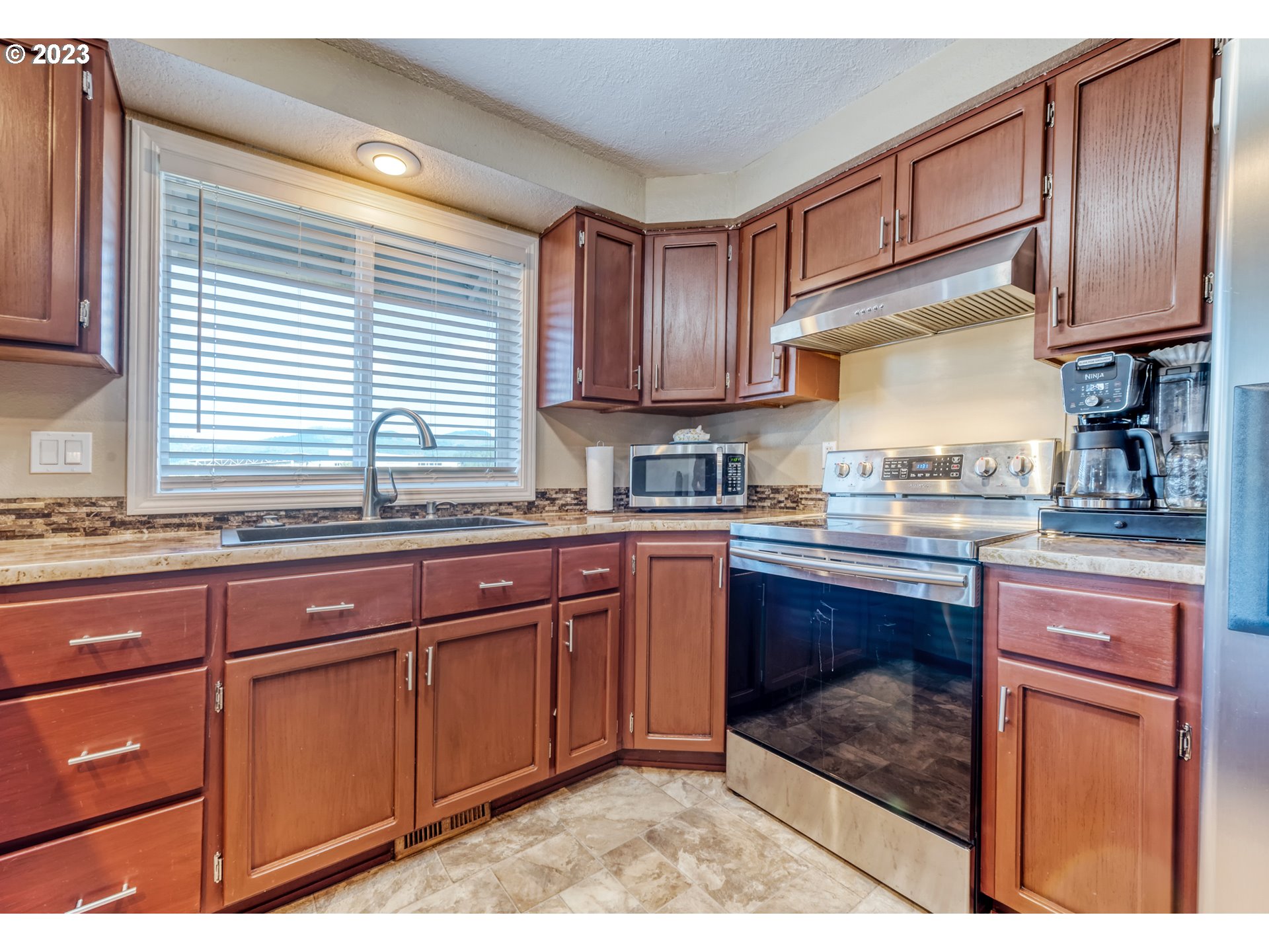 7370 B Street Springfield, OR 97478 - Photo 12 of 41 a kitchen with granite countertop wooden cabinets stainless steel appliances a sink and a window