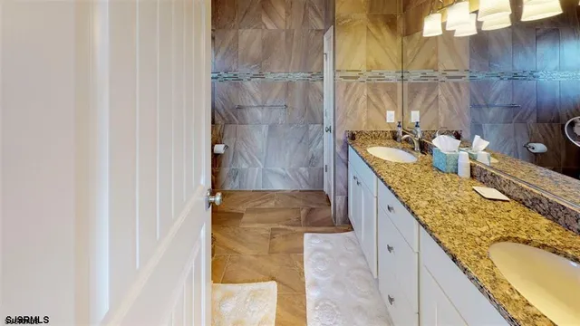 a bathroom with a granite countertop sink a mirror and shower