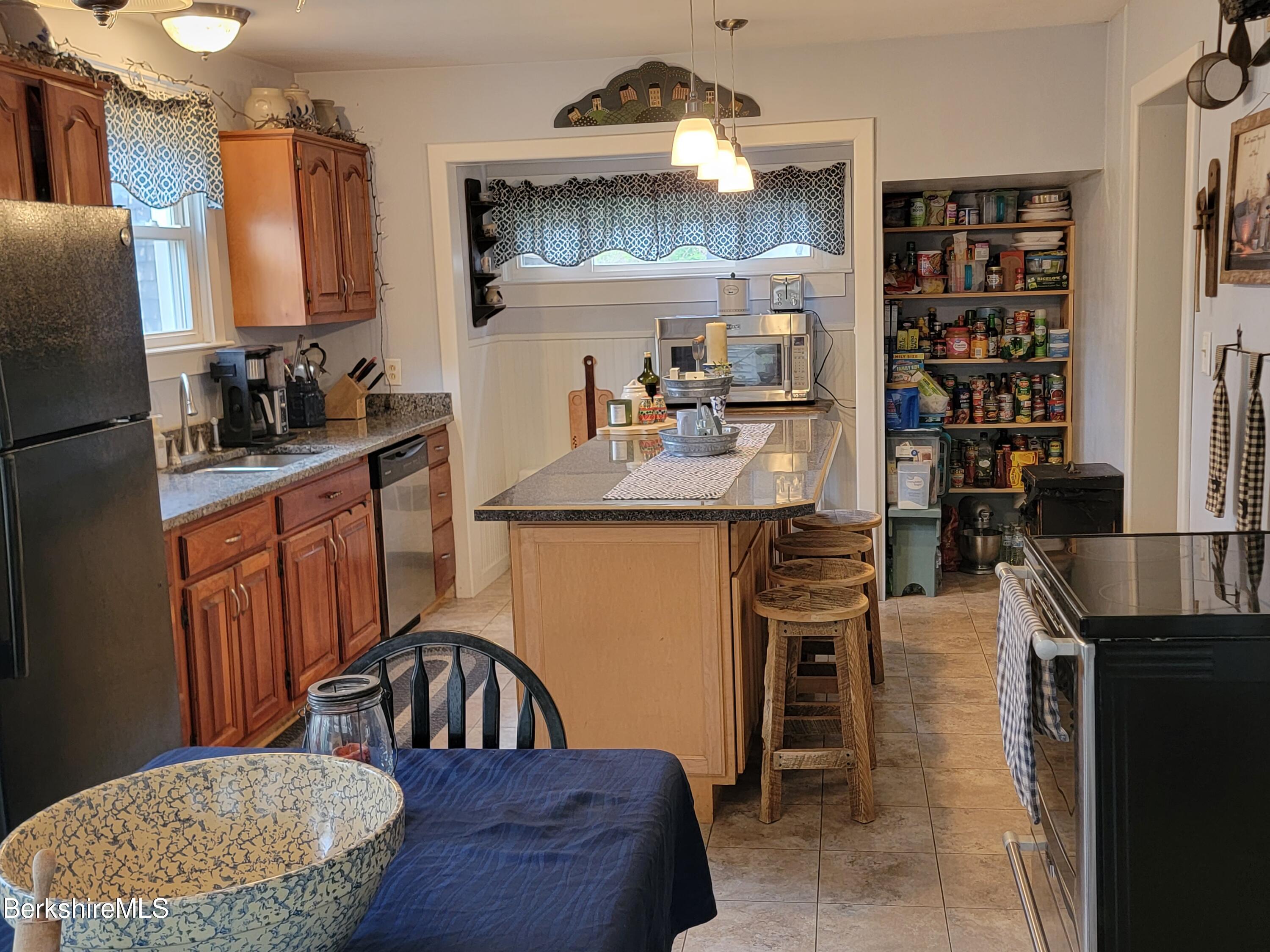 70 Frederick Street North Adams, MA 01247 - Photo 4 of 37 a kitchen with stainless steel appliances granite countertop a stove a sink dishwasher a refrigerator a dining table and chairs with wooden floor