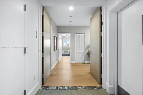 a view of a hallway with wooden floor and a bathroom