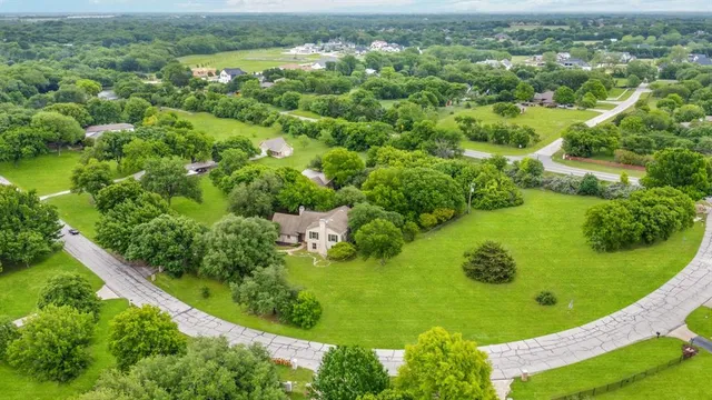 an aerial view of a residential houses with outdoor space and trees all around