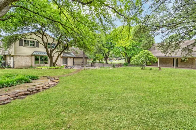 a view of a house with a big yard and large trees