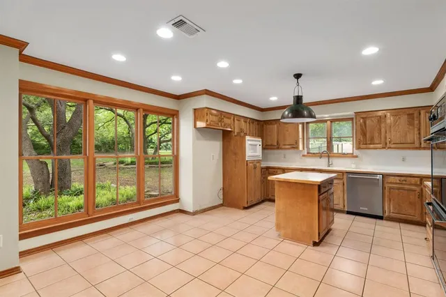 a large kitchen with stainless steel appliances kitchen island granite countertop a refrigerator and a sink