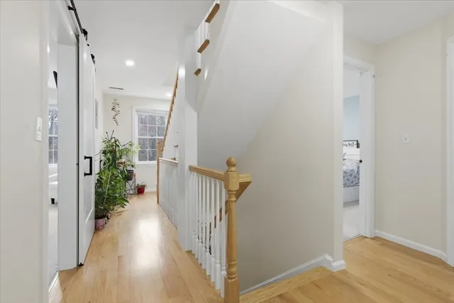 a view of a hallway with wooden floor and a bathroom