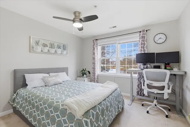 a bedroom with a bed a desk and chair with a large mirror