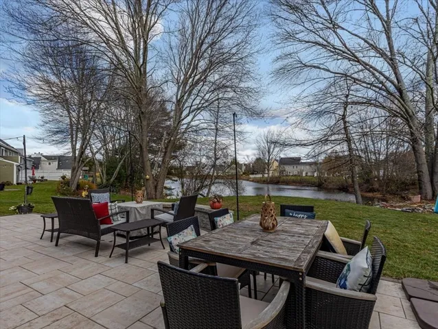 a view of a patio with table and chairs and a barbeque with potted plants and large trees