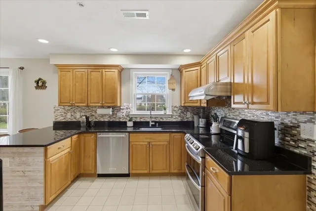 a kitchen with stainless steel appliances granite countertop a stove a sink and a microwave