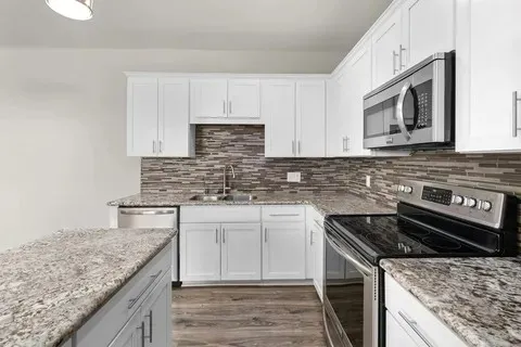 a kitchen with white cabinets and stainless steel appliances