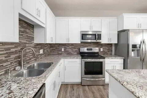 a kitchen with stainless steel appliances granite countertop a sink stove and cabinets