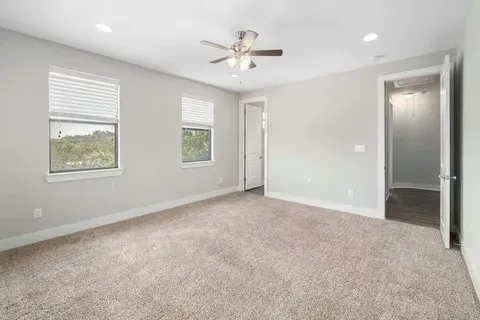 an empty room with windows and ceiling fan