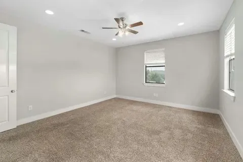 an empty room with windows and ceiling fan