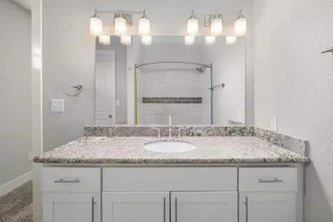 a bathroom with a granite countertop sink a mirror and a bathtub