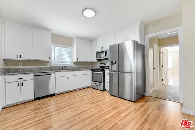 a kitchen with granite countertop a refrigerator and white cabinets