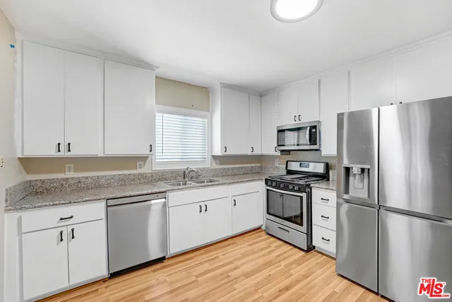 a kitchen with a sink a refrigerator and white cabinets