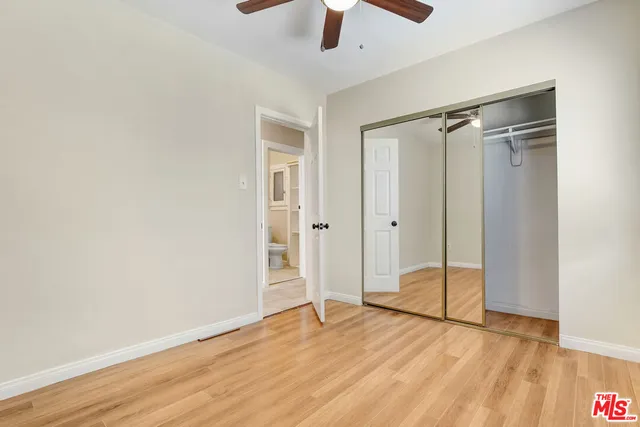 a view of an empty room with wooden floor a ceiling fan