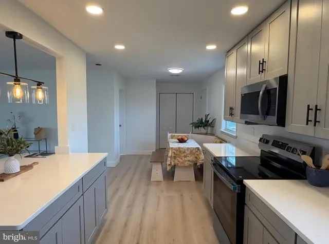 a large kitchen with stainless steel appliances a large counter top a stove and a sink